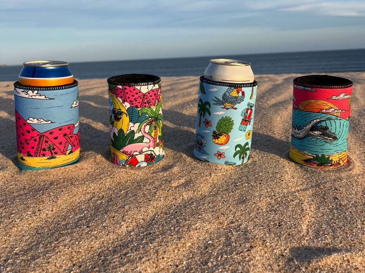 Four Stubbyz stubby holders lined up on the sand at the beach